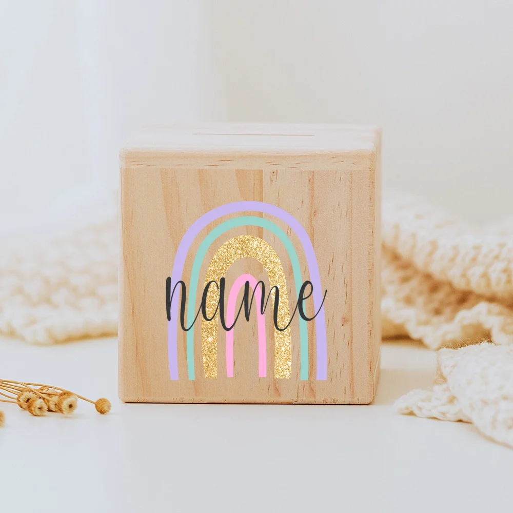 Descubra o Mealheiro Infantil Personalizado - Arco-Íris, feito em madeira maciça e personalizado com o nome da criança. Um presente único e educativo para decorar o quarto do bebé e incentivar a poupança. Ideal para nascimentos, batizados e aniversários!