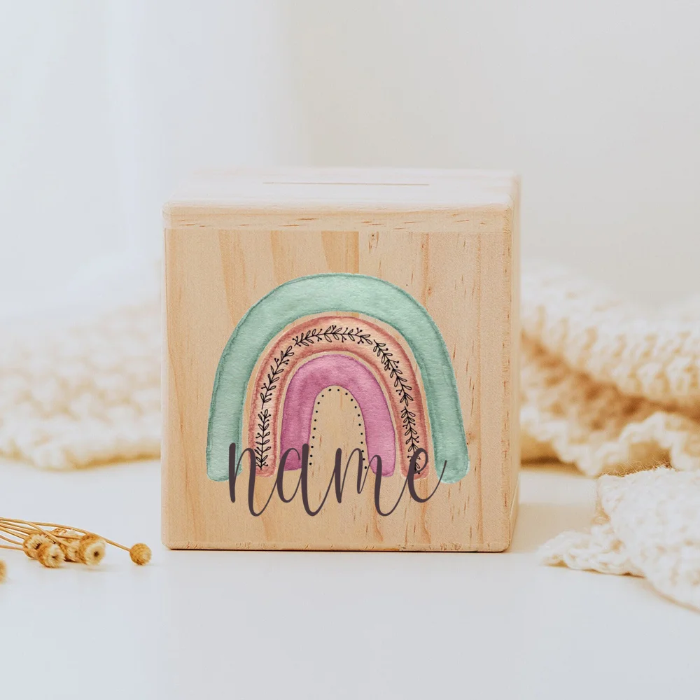 Descubra o Mealheiro Infantil Personalizado - Arco-Íris, feito em madeira maciça e personalizado com o nome da criança. Um presente único e educativo para decorar o quarto do bebé e incentivar a poupança. Ideal para nascimentos, batizados e aniversários!