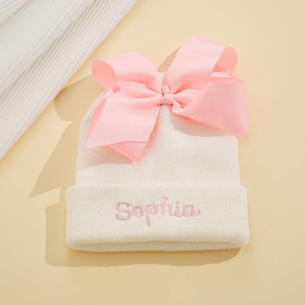 Personalize um adorável gorro de bebé com nome bordado e laço decorativo. Um presente original para nascimento, batizado, aniversário ou baby shower.
