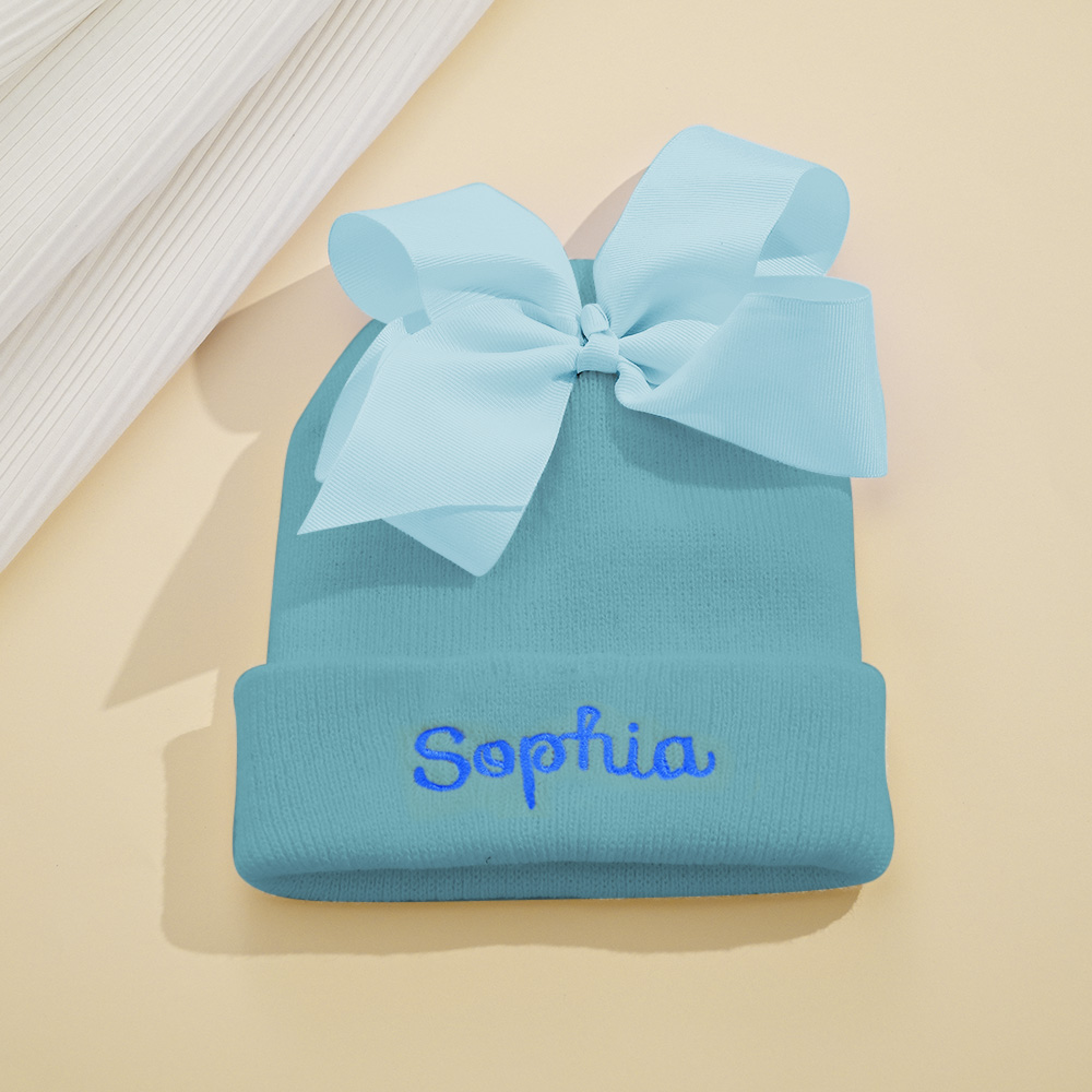 Personalize um adorável gorro de bebé com nome bordado e laço decorativo. Um presente original para nascimento, batizado, aniversário ou baby shower.
