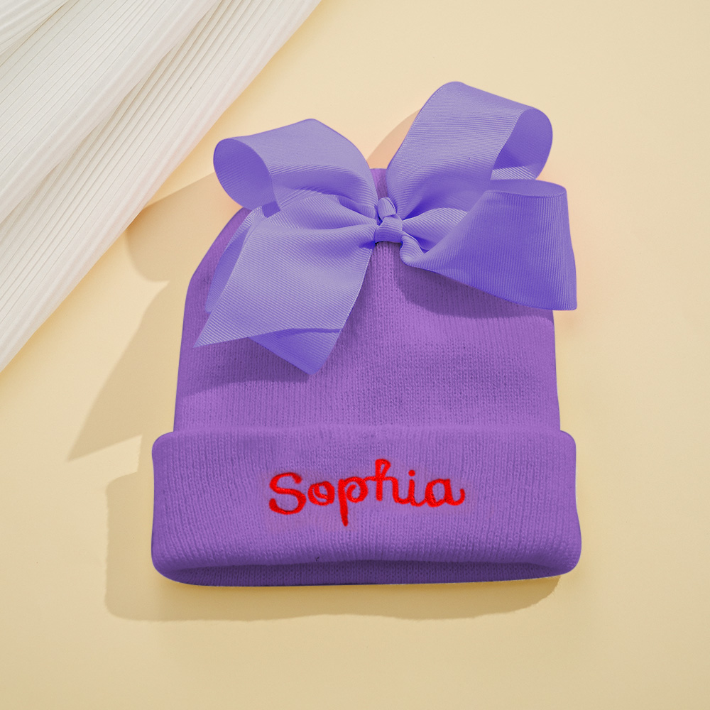 Personalize um adorável gorro de bebé com nome bordado e laço decorativo. Um presente original para nascimento, batizado, aniversário ou baby shower.